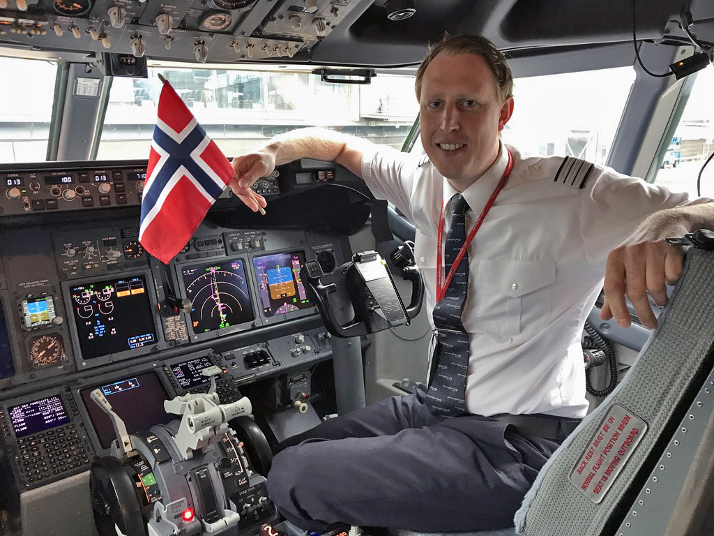 Pilot Mats Rove is sitting in the cockpit of an Boeing 737 with a Norwegian flag in his hand
